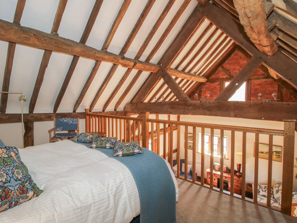 A bedroom with wooden beams and a bed at Courtyard Cottage in Little Stretton