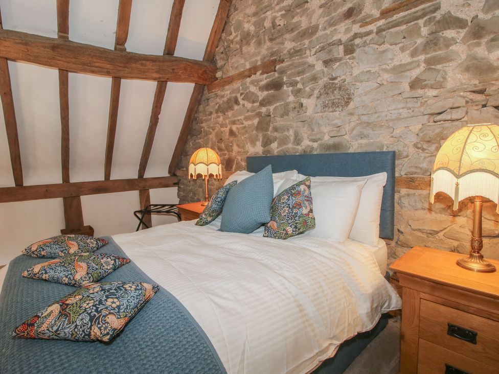 A bedroom with a bed and stone wall at Courtyard Cottage in Little Stretton