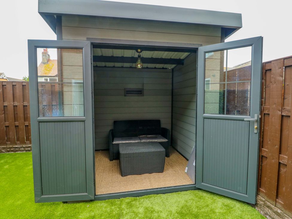 A garden shed with a sofa and coffee table at 20 Cysgod Y Bryn Rhos-On-Sea