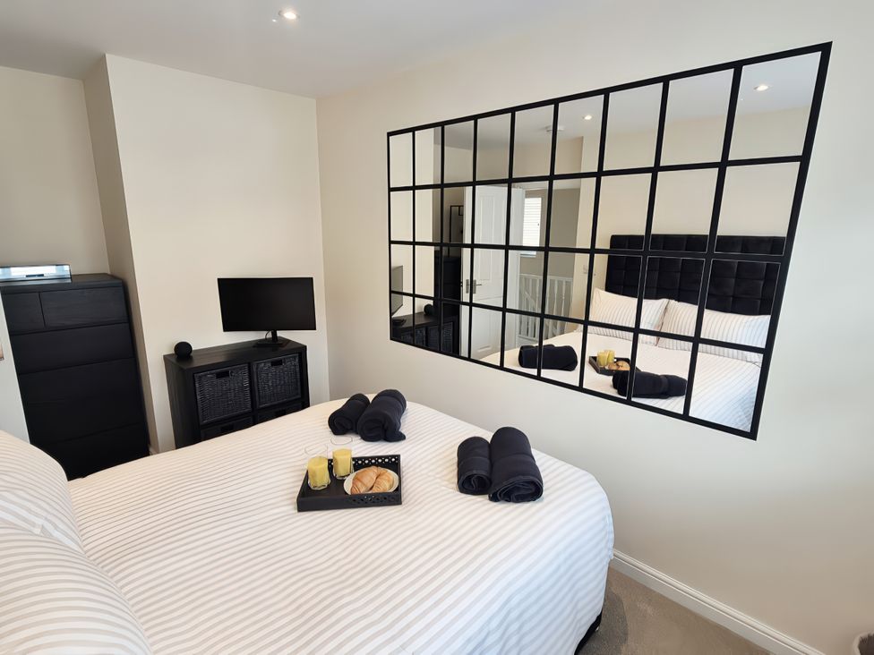 A bedroom with a bed and a mirror at Hafan Rhos in Rhos-On-Sea