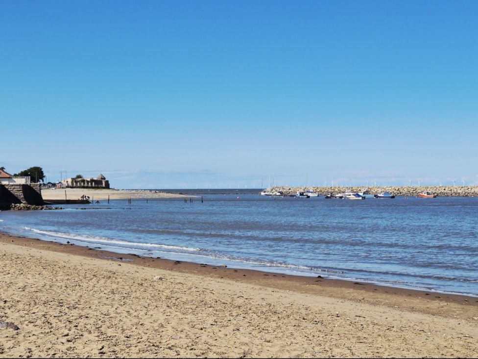 A beach with water and boats at Hafan Rhos in Rhos-On-Sea
