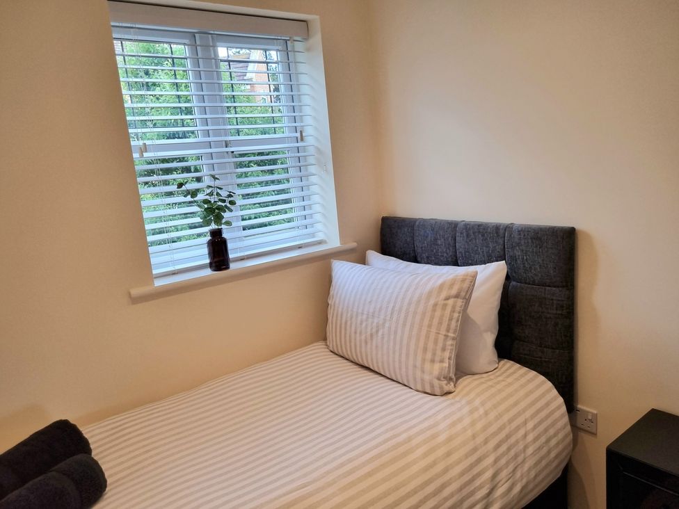 A bedroom with a bed and plant on the window at Hafan Rhos in Rhos-On-Sea