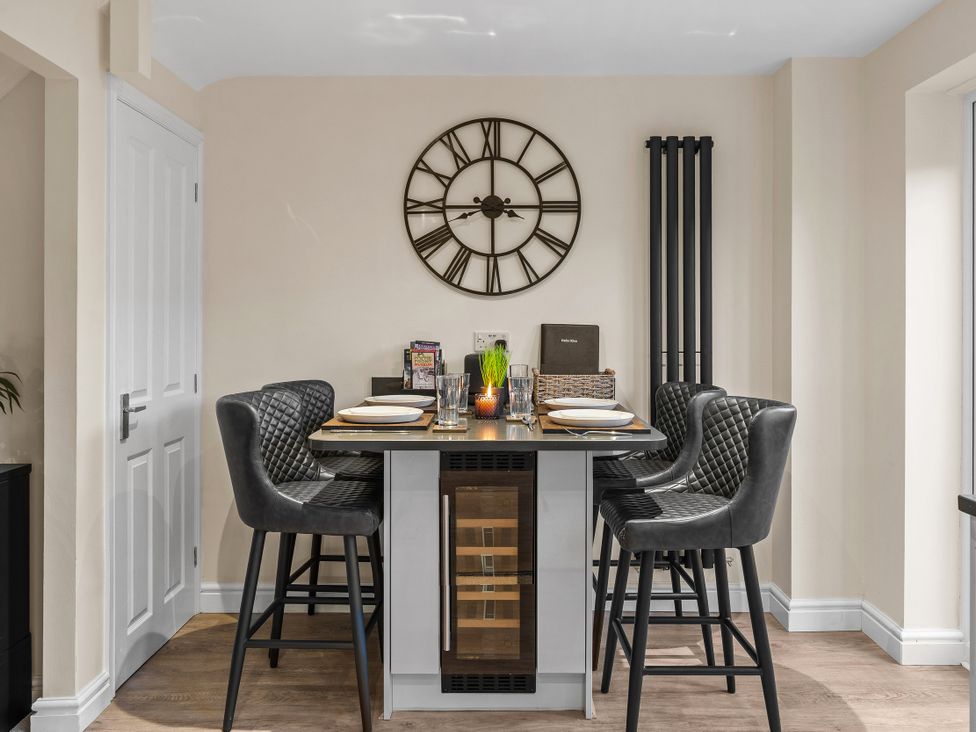 A kitchen with a dining table and bar stools at Hafan Rhos in Rhos-On-Sea