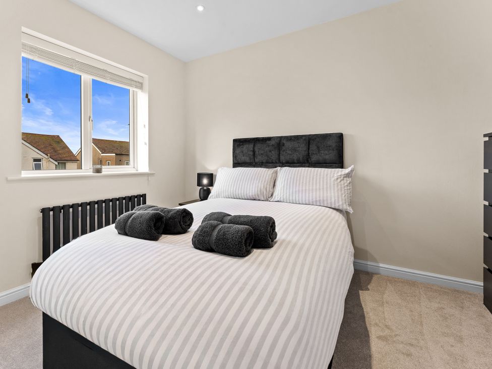 A bedroom with a bed and windows at Hafan Rhos in Rhos-On-Sea