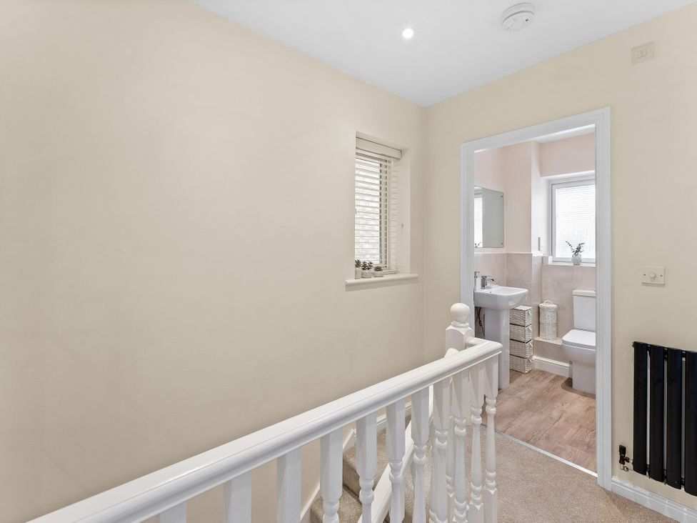 A bathroom with sink and toilet visible from a landing at Hafan Rhos in Rhos-On-Sea