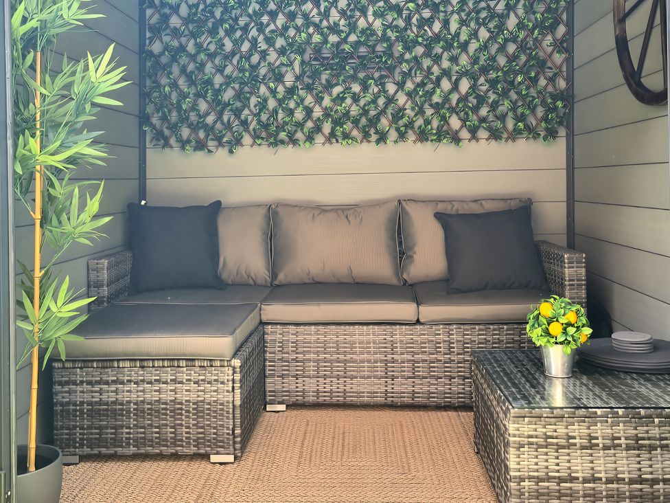 An outdoor seating area with a sectional sofa and a table at Hafan Rhos in Rhos-On-Sea