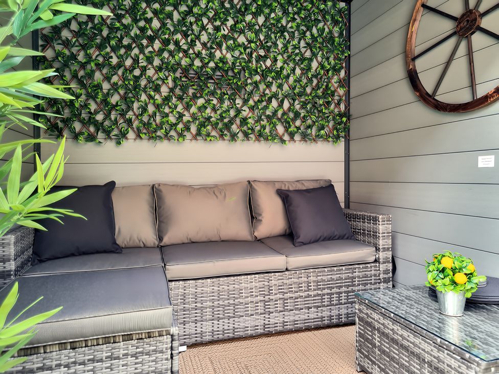 An outdoor seating area with a sofa and coffee table at Hafan Rhos in Rhos-On-Sea