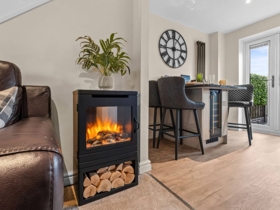 A living room with an electric fireplace and dining area at Hafan Rhos in Rhos-On-Sea