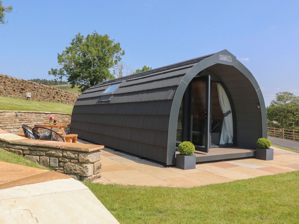 A cabin with outdoor seating and a stone wall at Ogden in Nelson