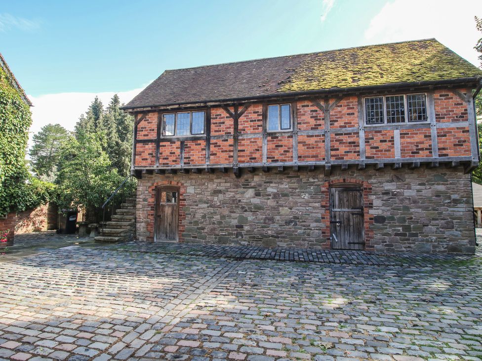 An outdoor view of a building with brick and stone walls at The Coach House in Little Stretton
