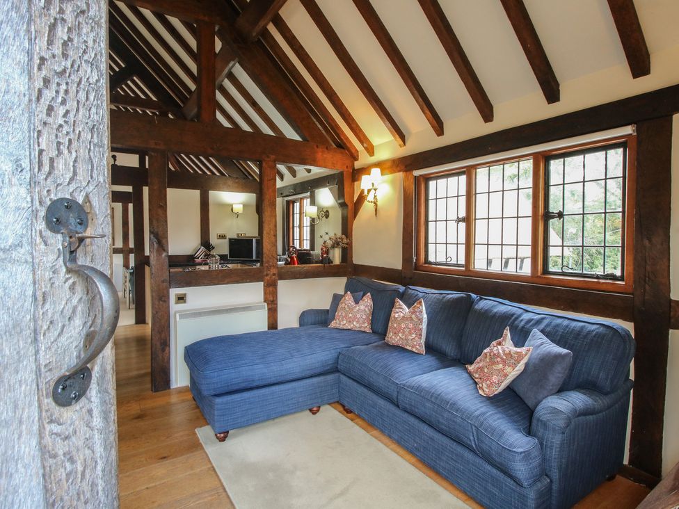A living room with a blue sofa and windows at The Coach House in Little Stretton