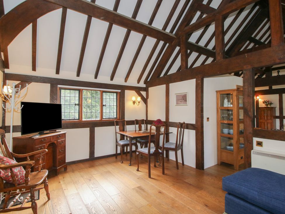 A living room with a dining table and television at The Coach House in Little Stretton