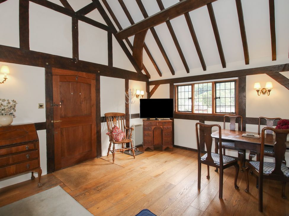 A living room with wooden furniture and windows at The Coach House in Little Stretton
