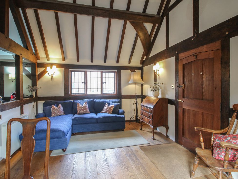 A living room with a blue sofa and wooden furniture at The Coach House Little Stretton
