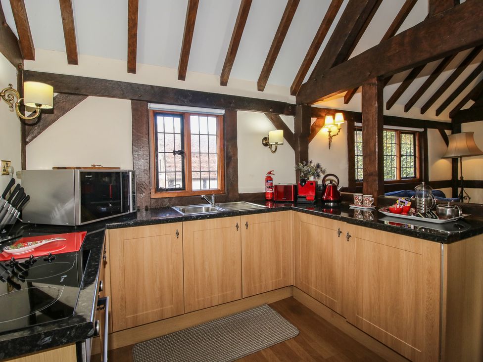 A kitchen featuring appliances and wooden cabinets at The Coach House in Little Stretton