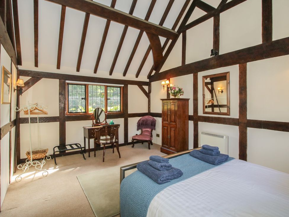A bedroom with a bed, wardrobe, and desk at The Coach House in Little Stretton