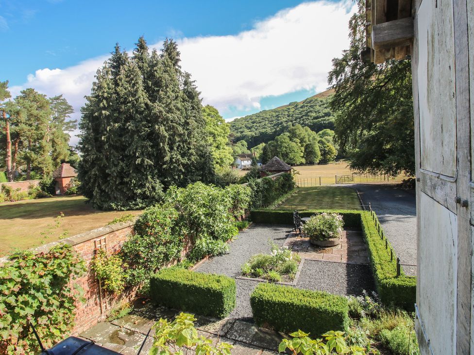 A garden view with trees and mountains at The Coach House in Little Stretton