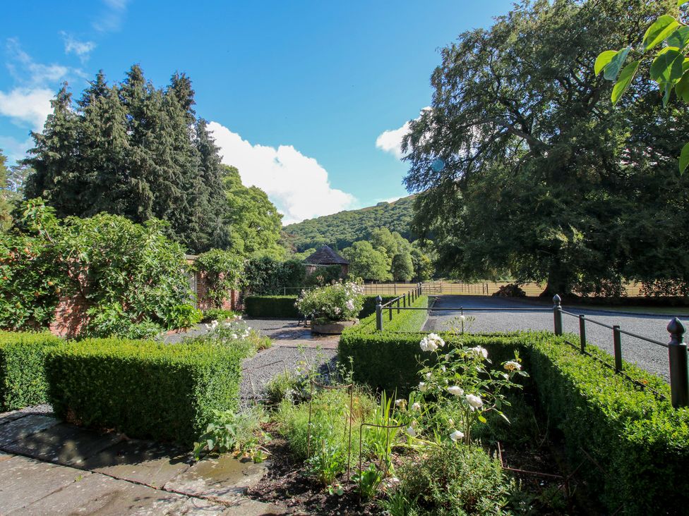 A garden with hedges and a gravel path at The Coach House in Little Stretton
