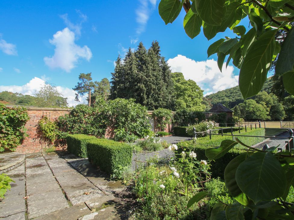 A garden with trees and hedges at The Coach House in Little Stretton