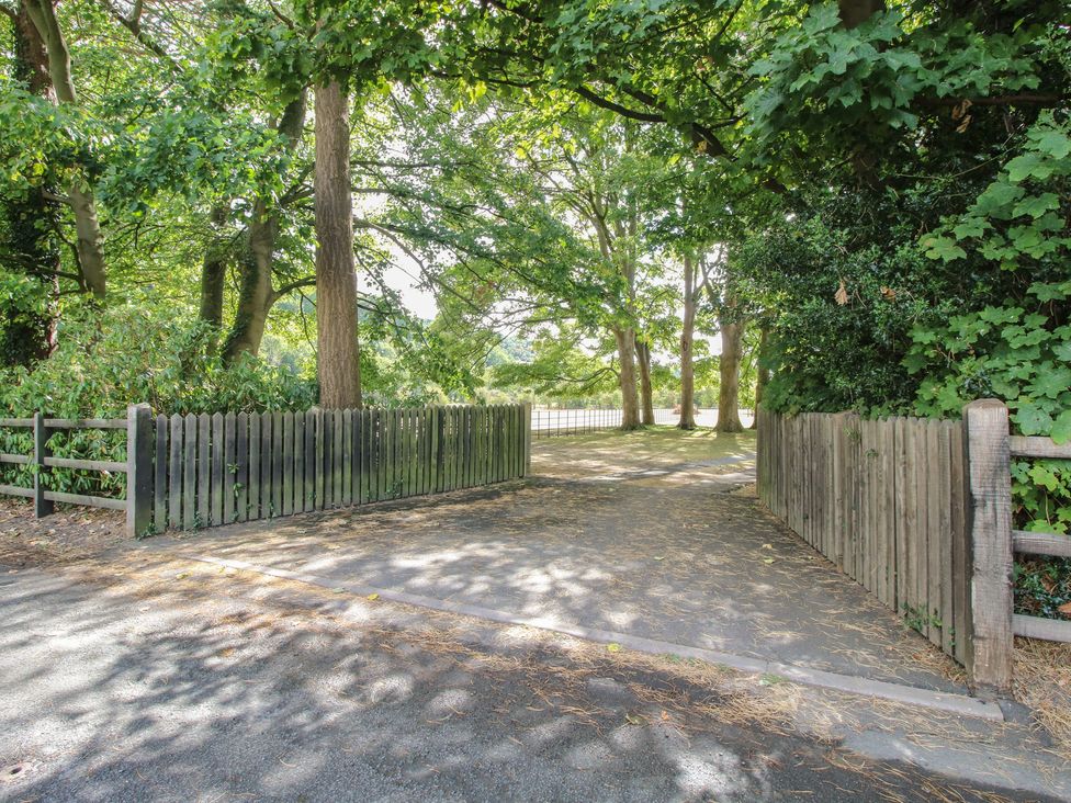 A pathway leading through wooden fences with trees at The Coach House in Little Stretton