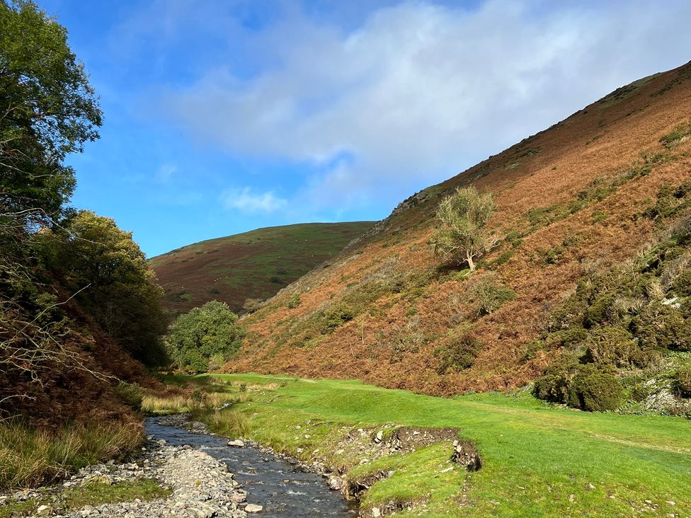 A stream with hills and trees at The Coach House in Little Stretton
