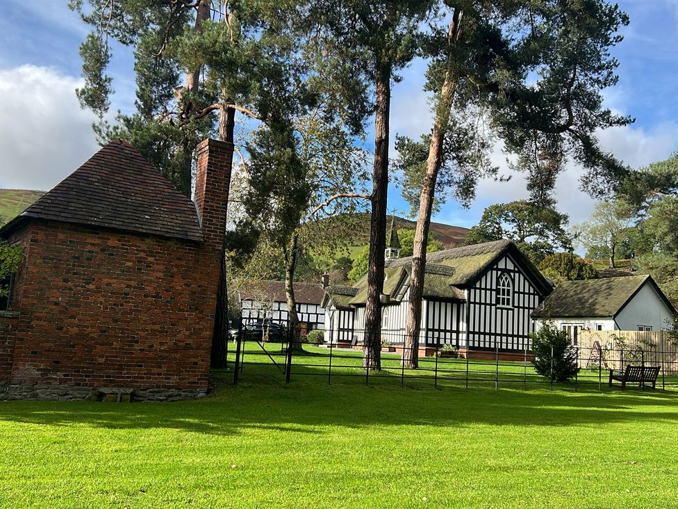 A view of a brick building and trees at The Coach House in Little Stretton