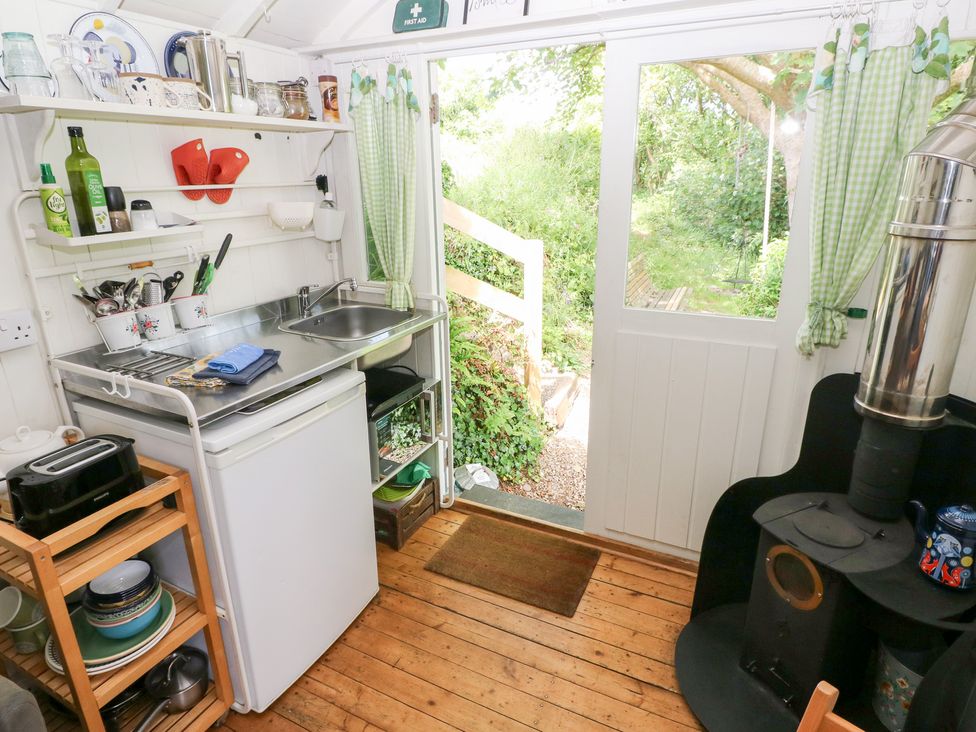 A kitchen with a sink and fridge at The Shephard Hut Nine Wells near Solva