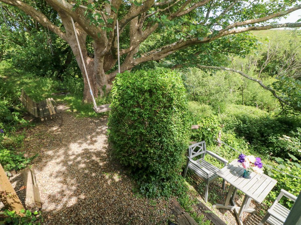A garden with a tree swing and a seating arrangement at The Shephard Hut near Solva