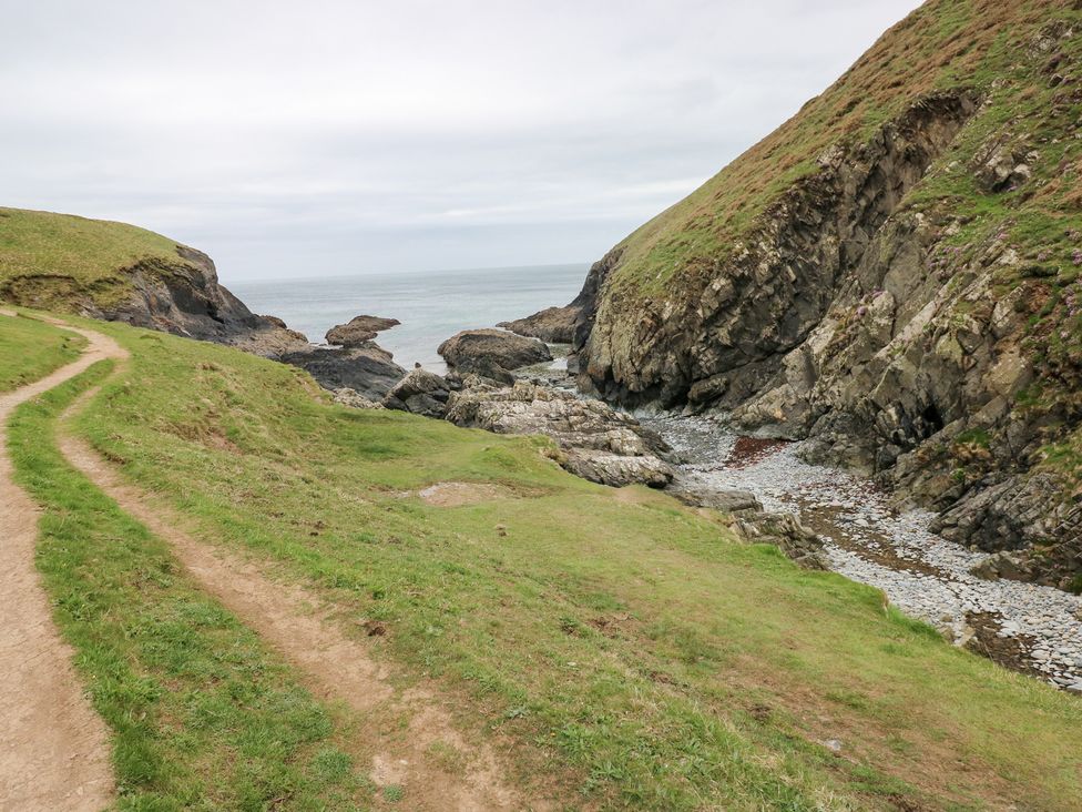 A coastal view with a pathway leading to the sea at The Shephard Hut Nine Wells near Solva
