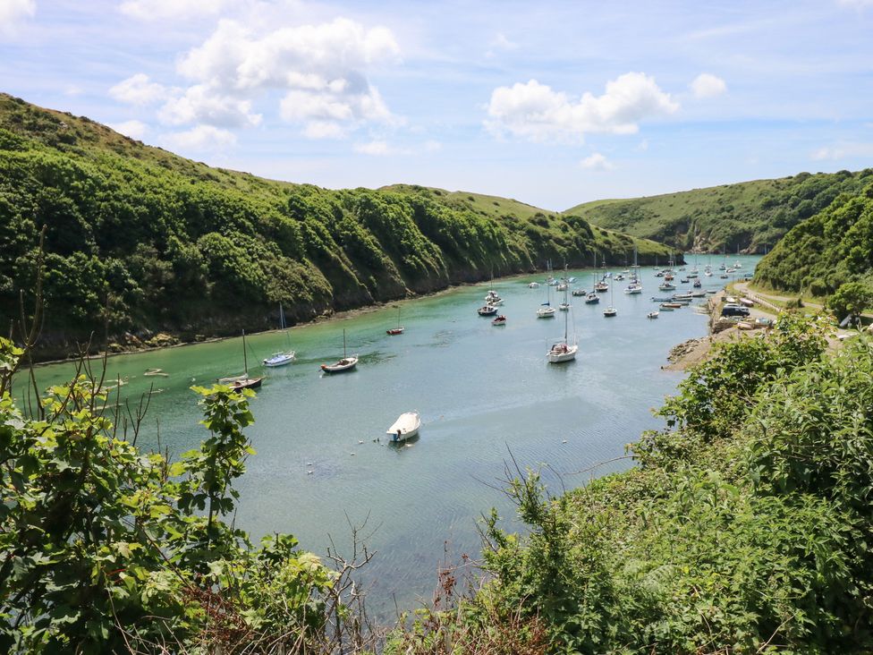A view of a river with boats and green hills at The Shephard Hut Nine Wells near Solva