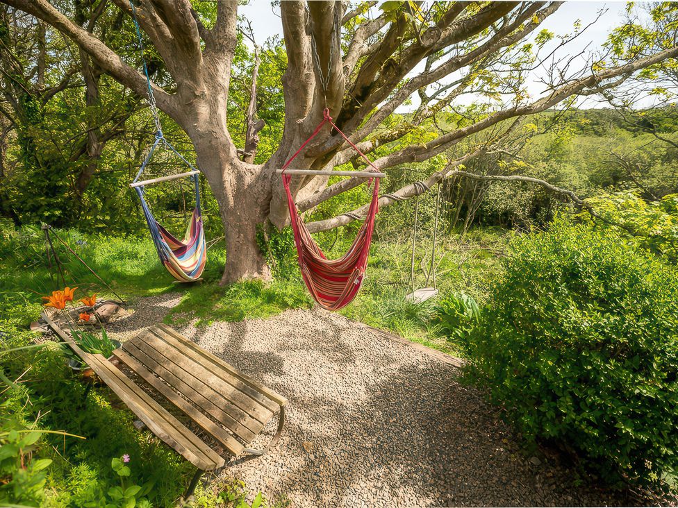 An outdoor area with two hammocks and a bench at The Shepherd Hut in Nine Wells near Solva