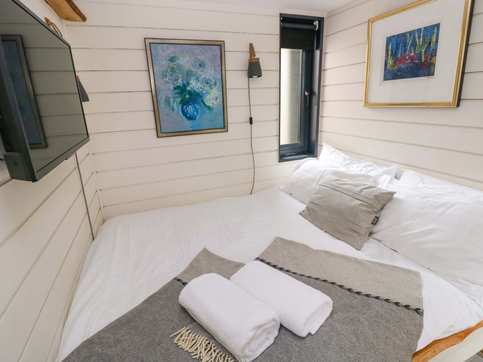 A bedroom with a bed, pillows, and wall art at The Tiny House in Nine Wells near Solva