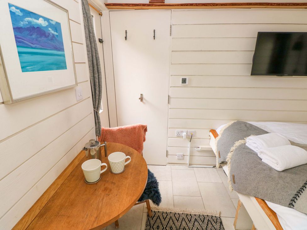 A bedroom with a bed, table, and television at The Tiny House in Nine Wells near Solva