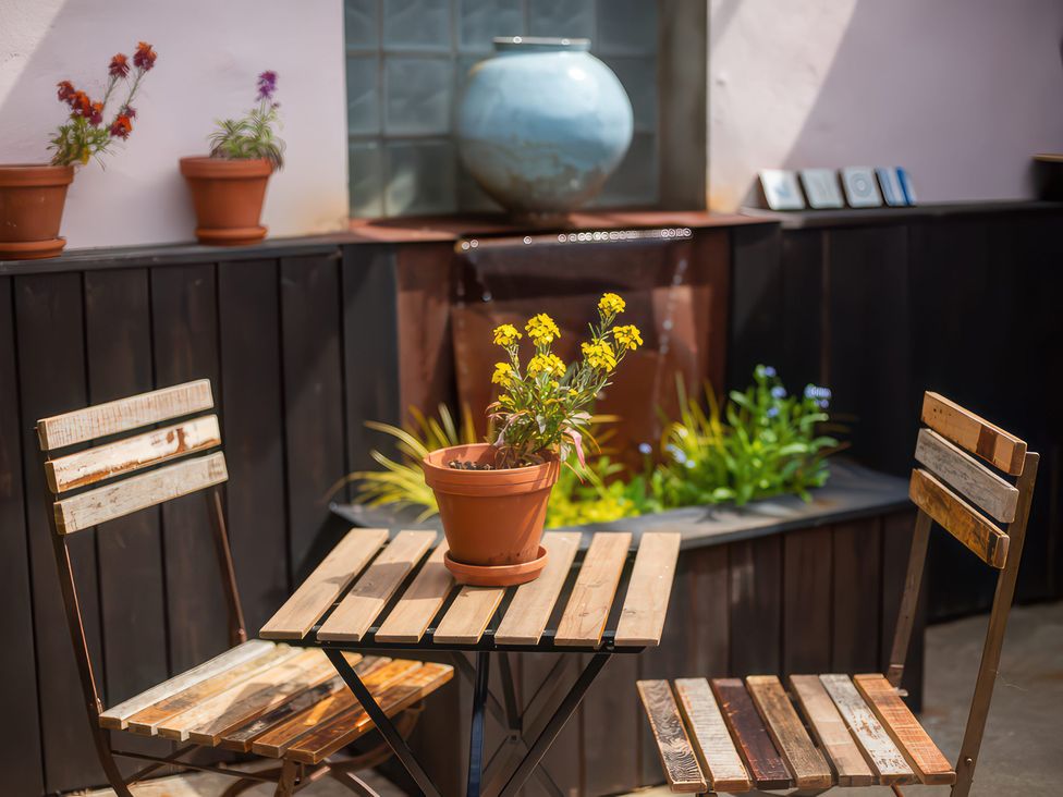 A garden with a table, two chairs and a potted plant at The Tiny House in Nine Wells near Solva