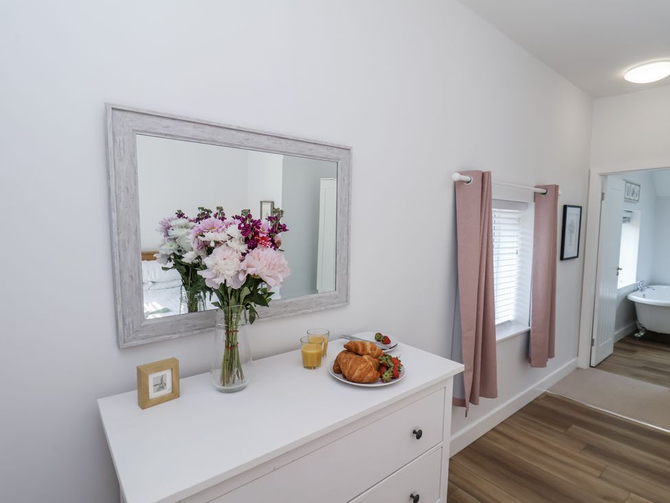 A bedroom with a mirror and flowers on a dresser at 96 Church Street in Guisborough
