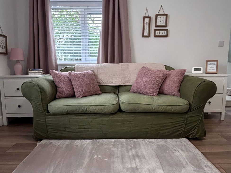A living room with a green sofa and cushions at 96 Church Street in Guisborough
