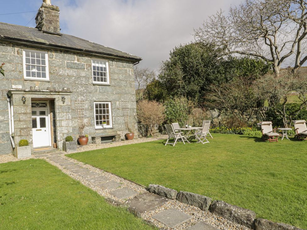 A garden with a house, chairs and a table at Bwthyn Morse in Llanfair