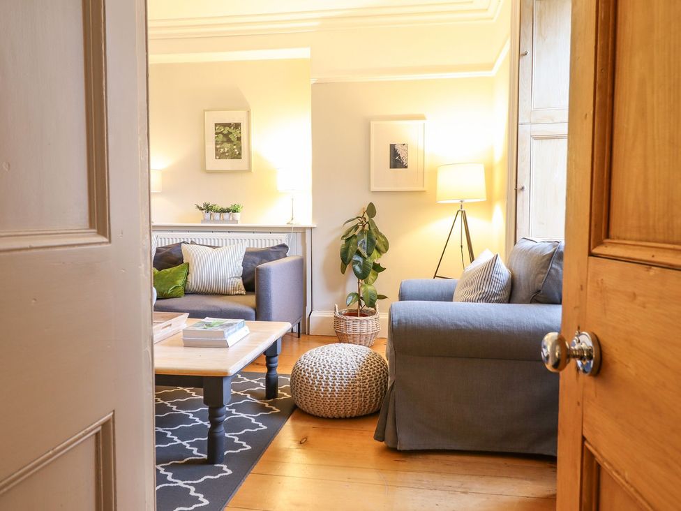A living room with a sofa, coffee table, and lamp at Bwthyn Morse in Llanfair