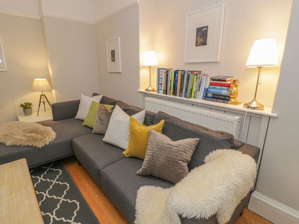 A living room with a sofa and books on a shelf at Bwthyn Morse in Llanfair