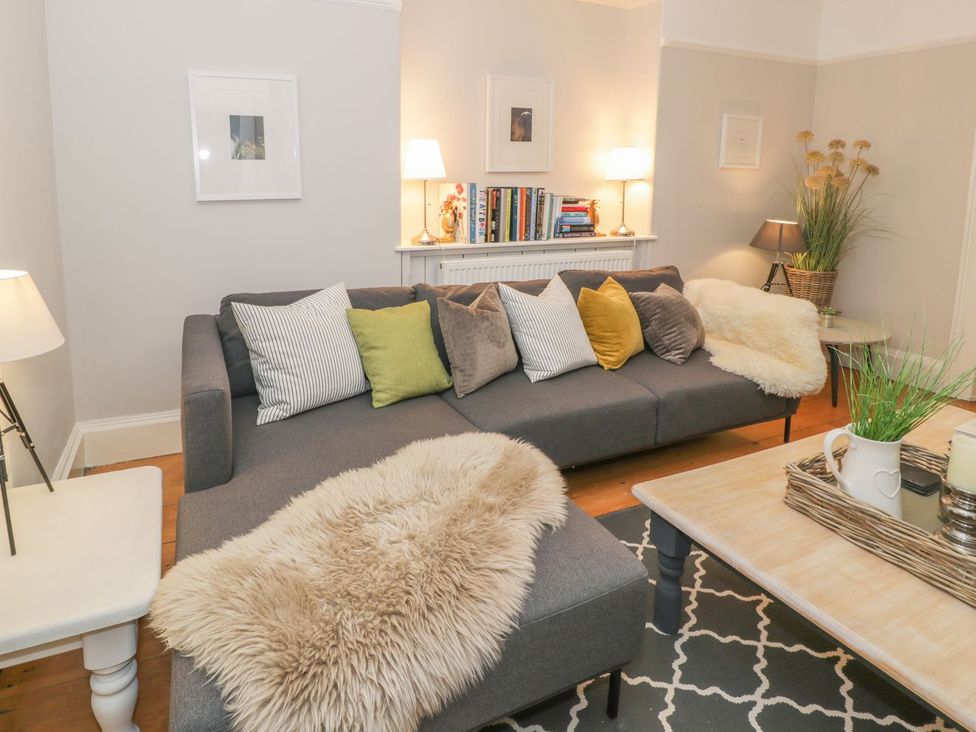 A living room with a sofa, bookshelves, and a lamp at Bwthyn Morse in Llanfair