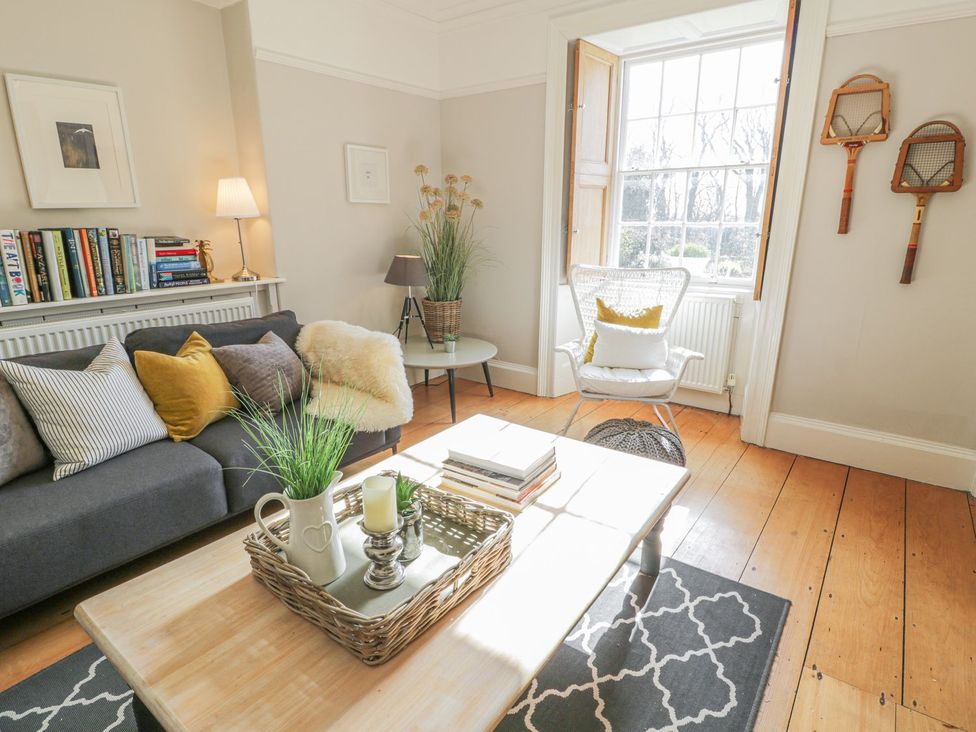 A living room with a sofa and books on a shelf at Bwthyn Morse in Llanfair