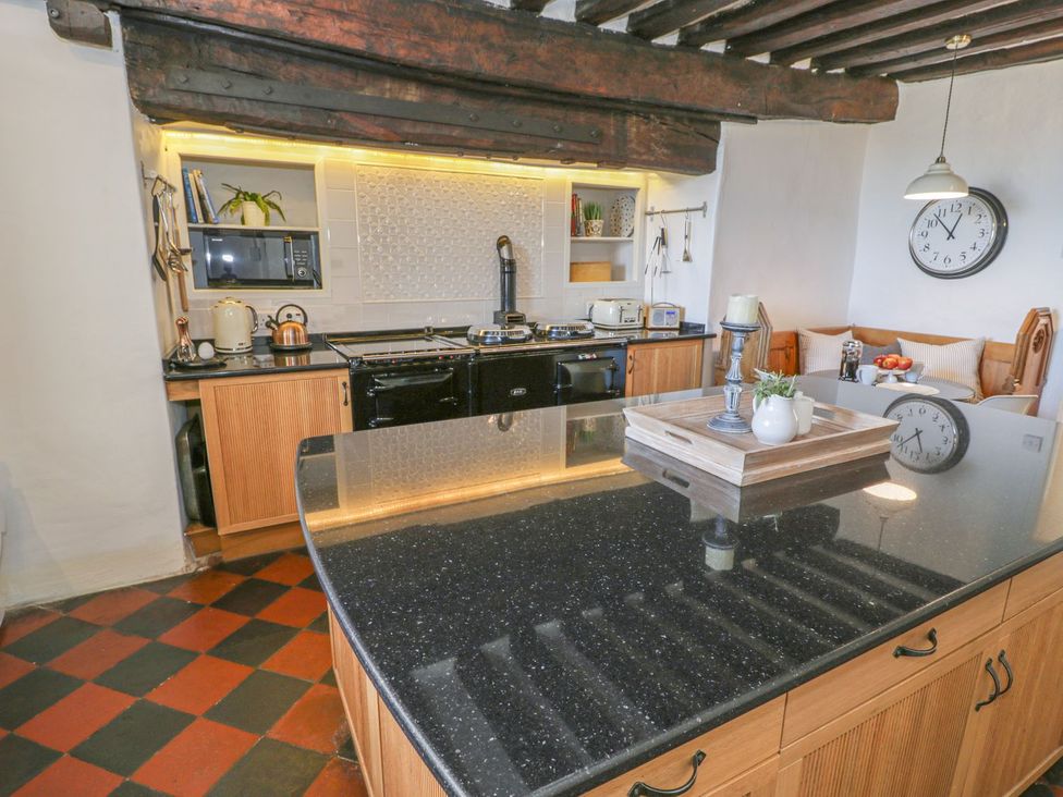 A kitchen with a stove, microwave, and dining area at Bwthyn Morse in Llanfair