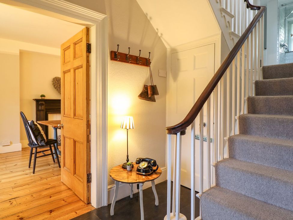 A hallway with a staircase and a table holding a lamp and a telephone at Bwthyn Morse in Llanfair