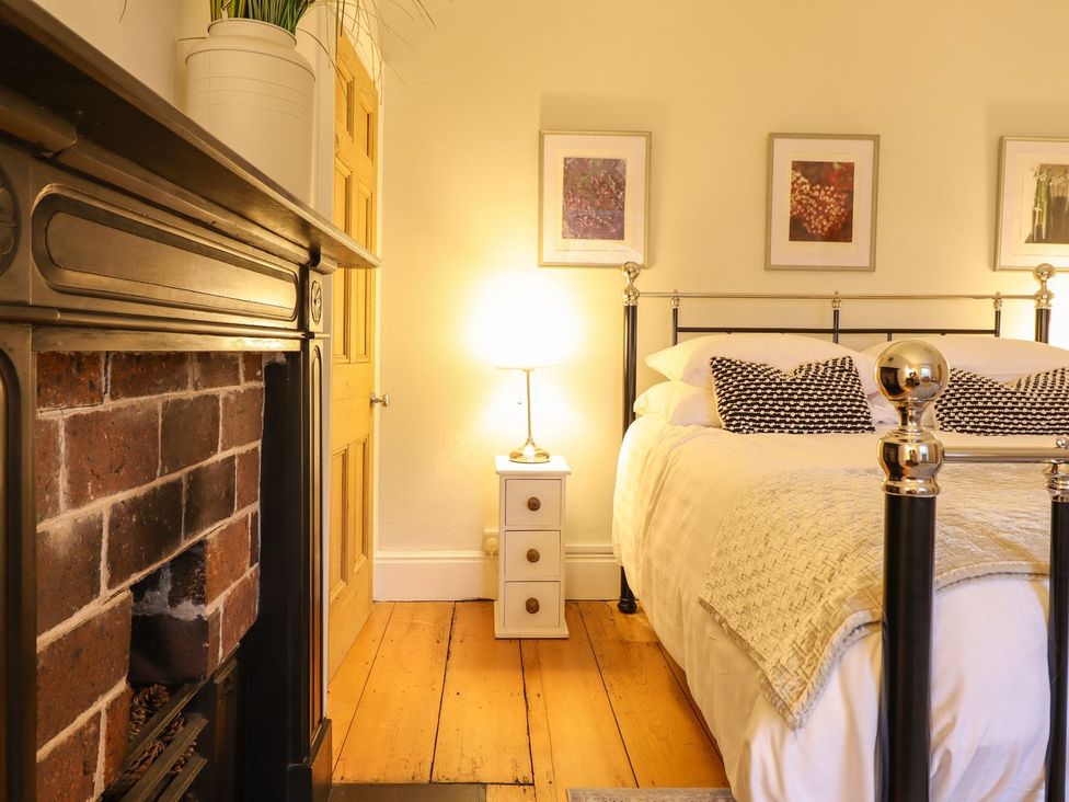 A bedroom with a bed, fireplace and nightstand at Bwthyn Morse Llanfair