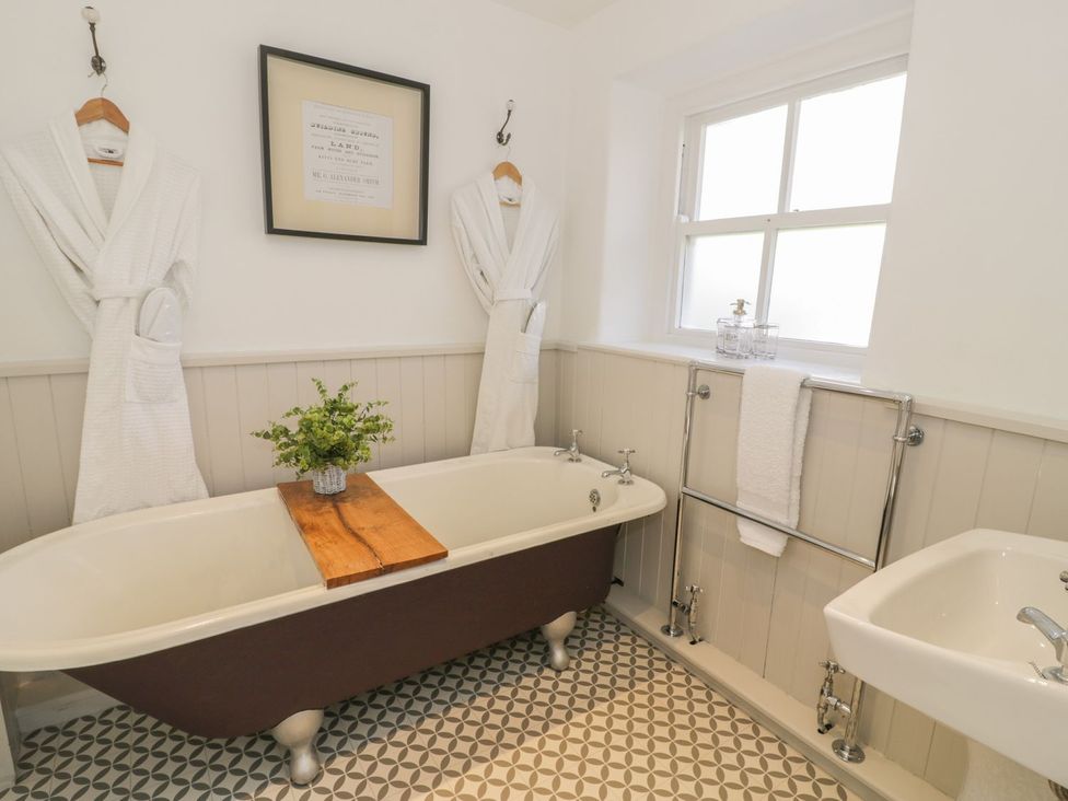 A bathroom with a bathtub, sink, and towels at Bwthyn Morse in Llanfair