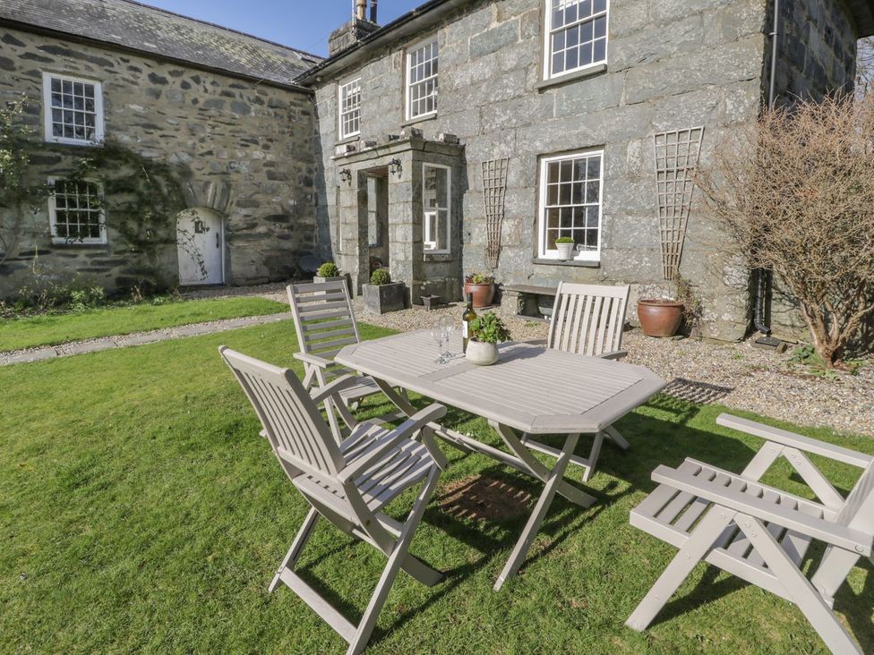 A garden with a table and chairs in front of a stone building at Bwthyn Morse Llanfair