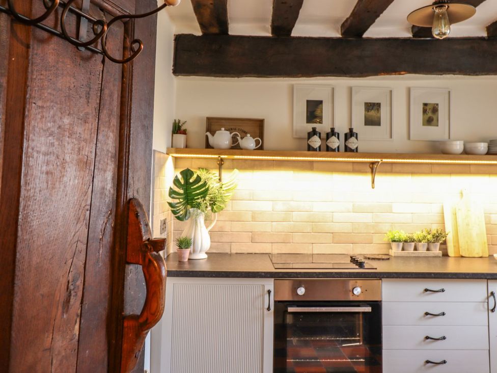 A kitchen featuring a door and shelves with kitchenware at Bwthyn Canol Llanfair