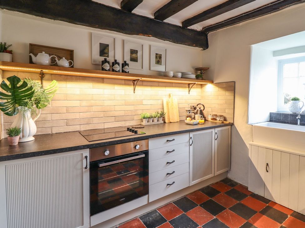 A kitchen with countertop, stove, and sink at Bwthyn Canol in Llanfair