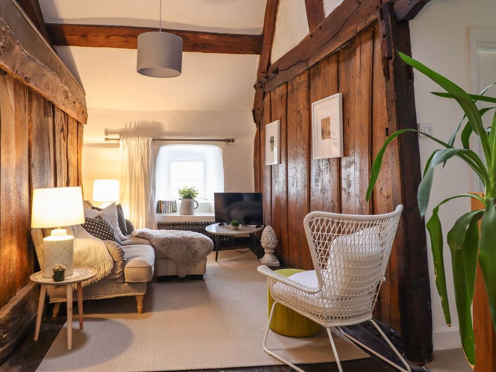 A living room with a sofa, lamp, and television at Bwthyn Canol in Llanfair