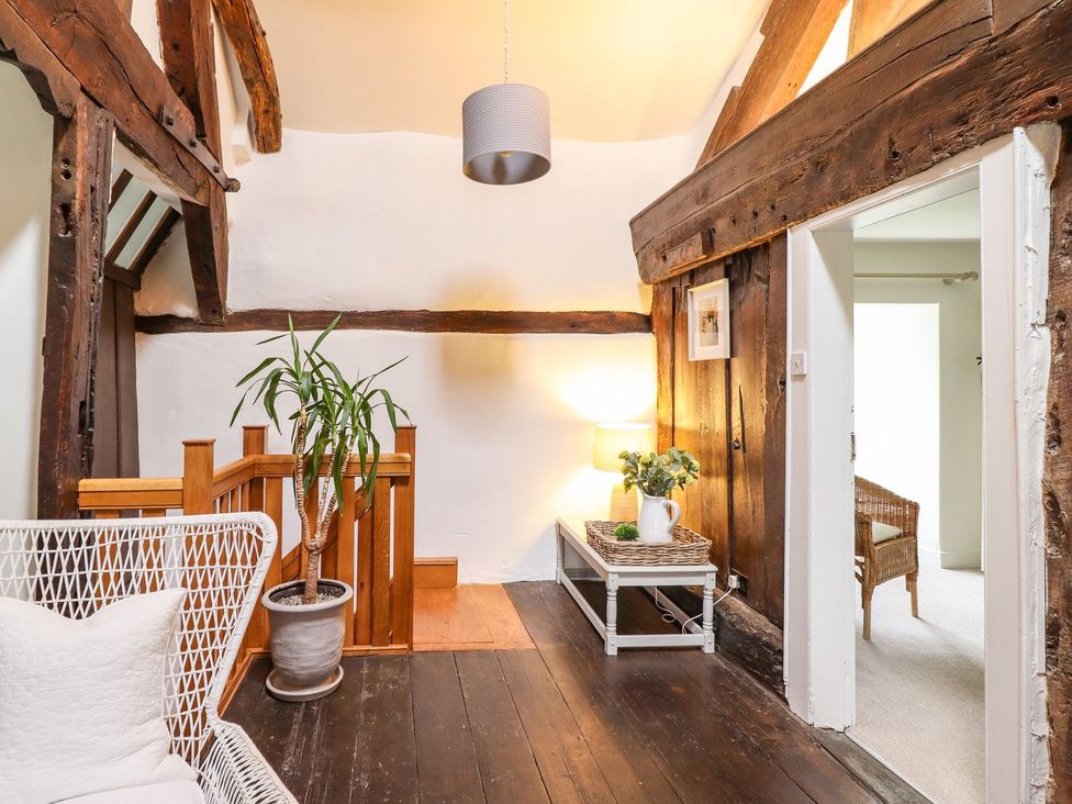 An entryway with a staircase and woven chair at Bwthyn Canol in Llanfair